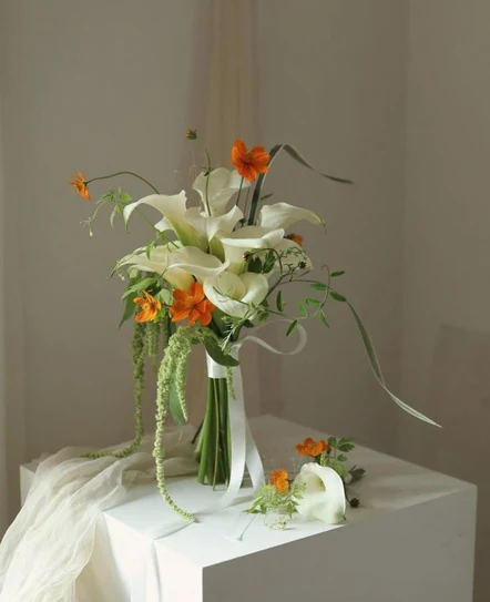 Sculptural white and green flowers with orange accents in the Tristen bouquet